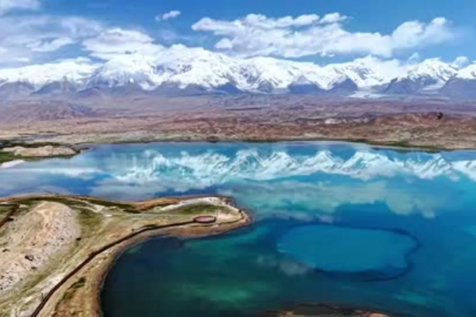 Karakul Lake below snow mountains in the Pamirs